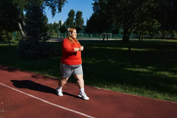 Una mujer de talla grande disfruta corriendo en un exuberante parque verde. — Stock Photo