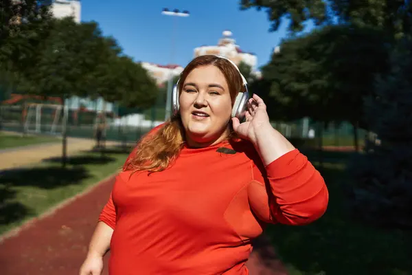 A beautiful plus size woman enjoys her workout outdoors in bright sunshine. — Stock Photo