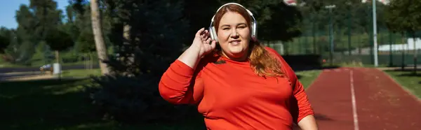 Una mujer confiada hace ejercicios al aire libre mientras usa auriculares. - foto de stock