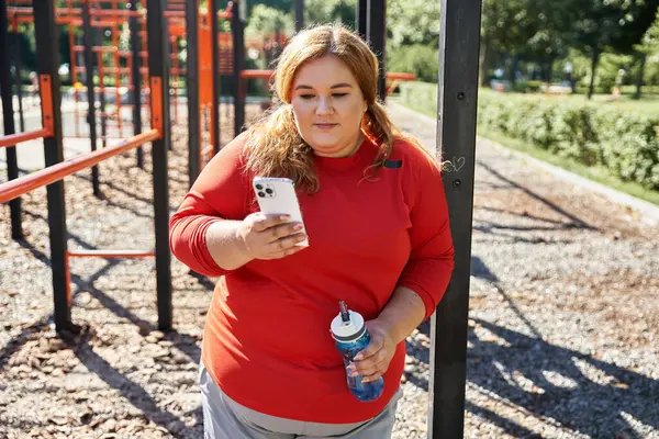 Una donna vivace controlla il suo telefono mentre rimane attiva all'aperto. — Foto stock