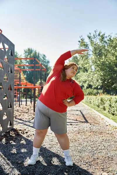 Una bella donna si allunga in un parco, abbracciando uno stile di vita sano con energia. — Foto stock