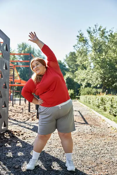 A plus size woman enjoys a refreshing stretch in a vibrant park. — Stock Photo