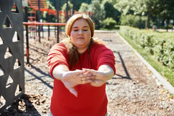 Una donna dedicata si allunga in un parco vibrante, godendo il suo allenamento. — Foto stock