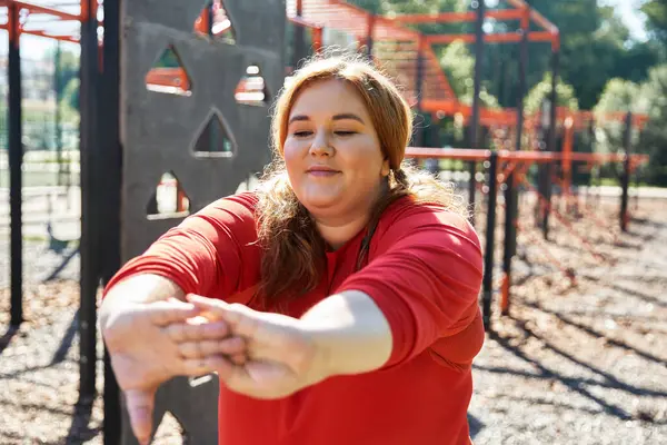 A plus size woman stretches gracefully in the park, embracing active living. — Stock Photo