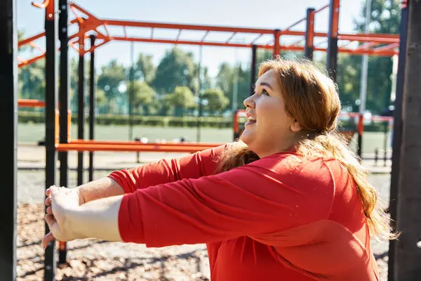 Una donna allegra si allunga mentre si gode il suo allenamento nel parco. — Foto stock