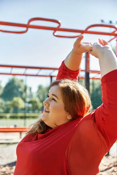 A cheerful woman stretches under the vibrant blue sky in the park. — Stock Photo