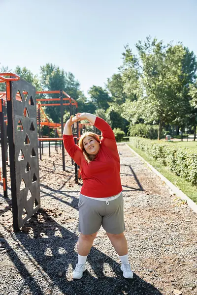Una donna plus size allunga felicemente sotto il caldo sole nel parco. — Foto stock