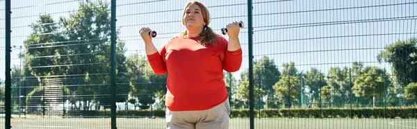 Eine fröhliche Frau stemmt Gewichte beim Sport im Freien bei strahlendem Sonnenlicht. — Stockfoto