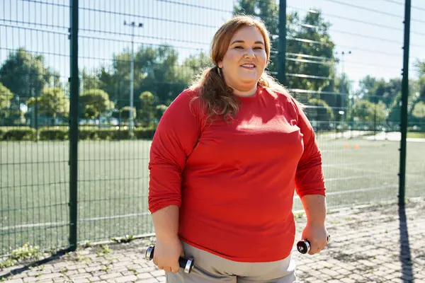 A beautiful plus size woman exercises with determination in a lively park. — Stock Photo