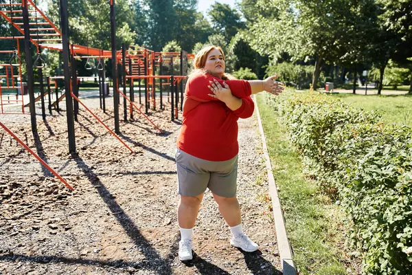 Una mujer de talla grande disfruta estirándose al aire libre en un parque. - foto de stock