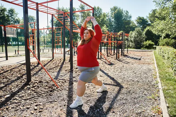 Une femme de taille plus effectue un exercice d'étirement à l'extérieur dans un parc animé. — Photo de stock