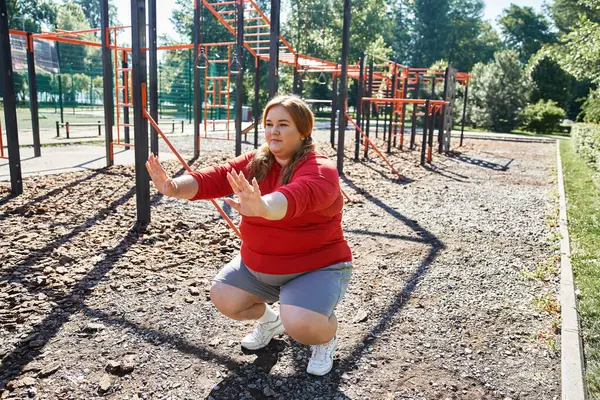 Una donna plus size si impegna in esercizio tra le attrezzature del parco. — Foto stock