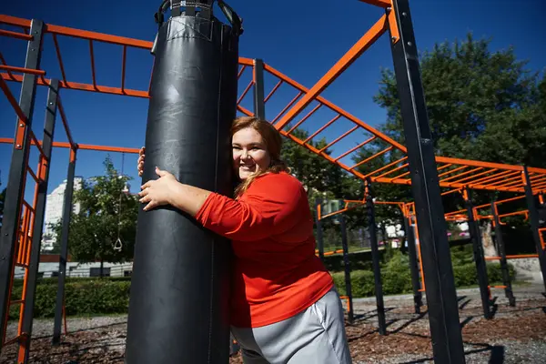 A beautiful plus size woman exercises enthusiastically in a sunny park. — Stock Photo