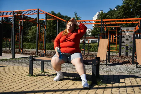 A confident plus size woman pauses during her workout in a sunny park environment. — Stock Photo