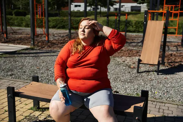 Una mujer de talla grande se toma un momento para descansar mientras hace ejercicio al aire libre. - foto de stock