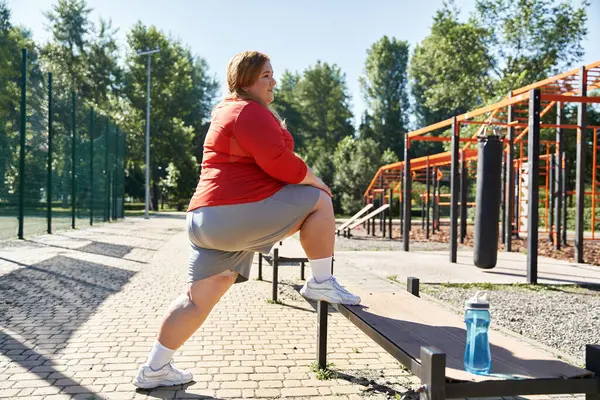 Una mujer se estira en un banco en un vibrante parque al aire libre. — Stock Photo