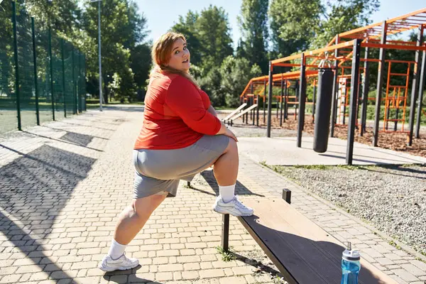 Una donna vivace gode la sua routine di esercizio in un parco soleggiato. — Foto stock