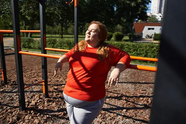 Женщина plus size занимается на свежем воздухе, впитывая солнечный свет в оживленном парке. — стоковое фото