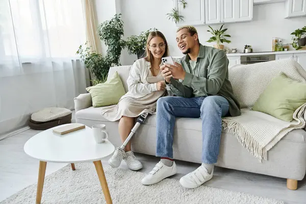 Friends share laughter while exploring a phone together on a comfortable couch. — Stock Photo