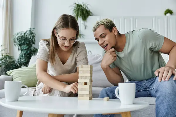 Friends share laughter and focus while playing Jenga together indoors. — Stock Photo