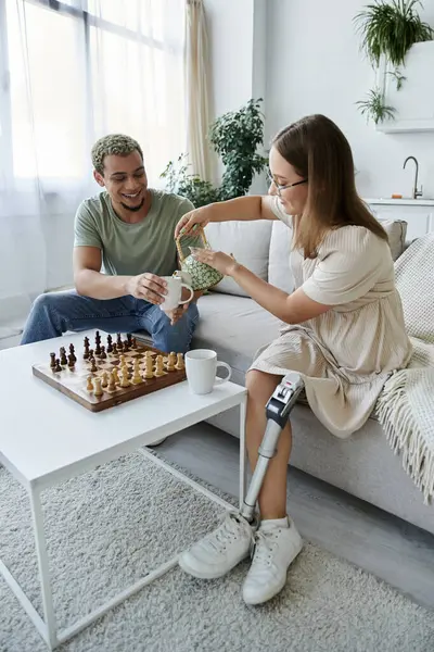 Deux amis partagent le thé et le rire tout en jouant aux échecs à la maison. — Photo de stock