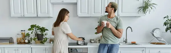 A non binary person enjoys a friendly chat while a woman cooks. — Stock Photo
