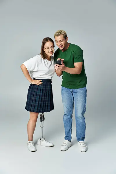Two friends share joy while looking at a device, one with a prosthetic leg. — Stock Photo