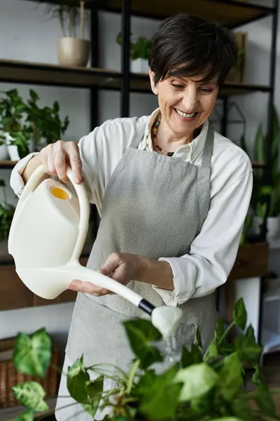 A gardener happily waters lush greenery surrounded by vibrant plant life. — Stock Photo