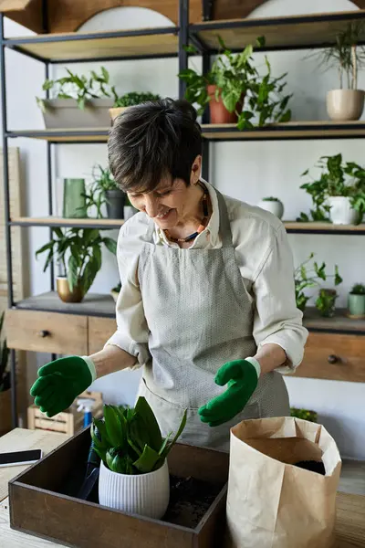 Une femme s'occupe joyeusement de ses plantes en portant des gants de jardinage. — Photo de stock