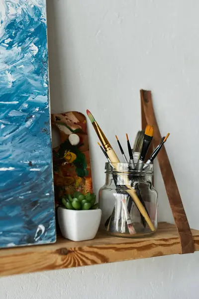 Brushes near painting in studio. — Stock Photo