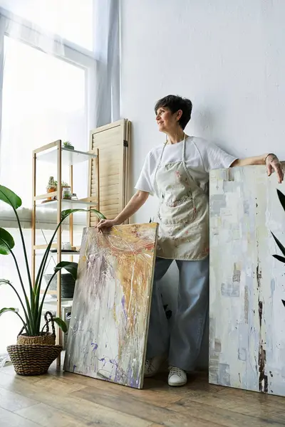 Une femme mûre explore joyeusement sa passion pour la peinture dans un studio lumineux. — Photo de stock