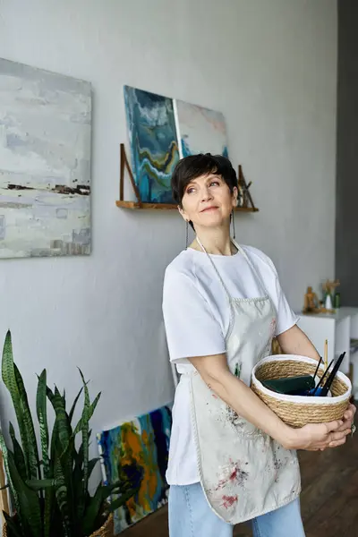 An enthusiastic painter engages with her artwork in a bright studio. — Stock Photo