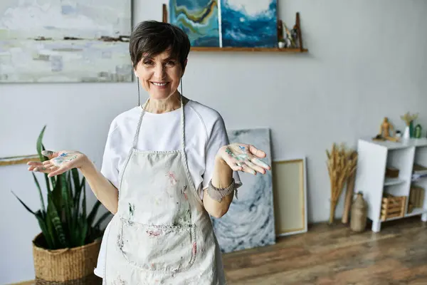 A joyful artist showcases her colorful hands in a sunlit creative space. — Stock Photo