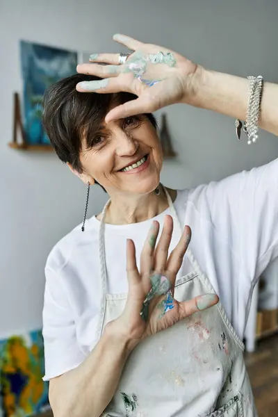 A happy woman with paint covered hands enjoys her artistic process. — Stock Photo