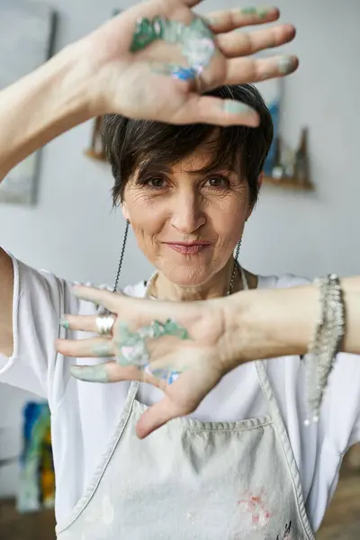 A passionate artist engages in painting with colorful hands in her creative space. — Stock Photo