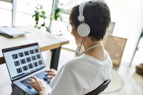 A woman with headphones discovers art inspiration at her creative workspace. — Stock Photo