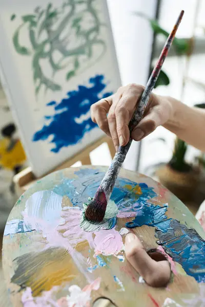 A mature woman blends colors on her palette, immersed in her artistic process. — Stock Photo