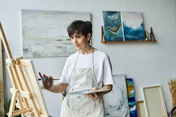 A woman joyfully creates art in her inviting studio space. — Stock Photo