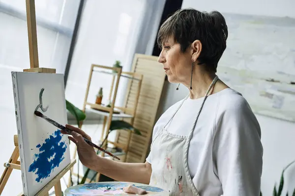 A woman focuses intently on her canvas, creating a vibrant artwork. — Stock Photo