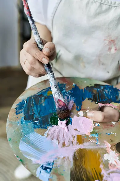 A dedicated painter blends vibrant colors on her palette with an artistic touch. — Stock Photo