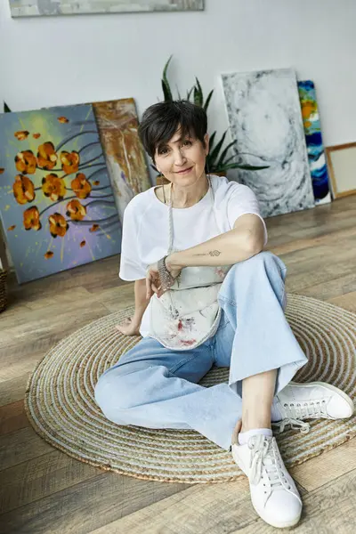 Une peintre se détend dans son atelier, entourée de ses œuvres vibrantes. — Photo de stock