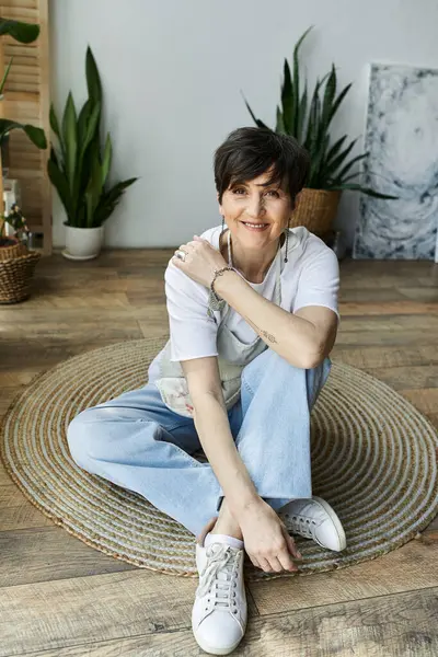 A joyful woman creates art while seated on a woven rug. — Stock Photo