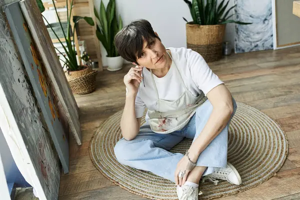 A painter enjoys her creative process surrounded by vibrant art and plants. — Stock Photo