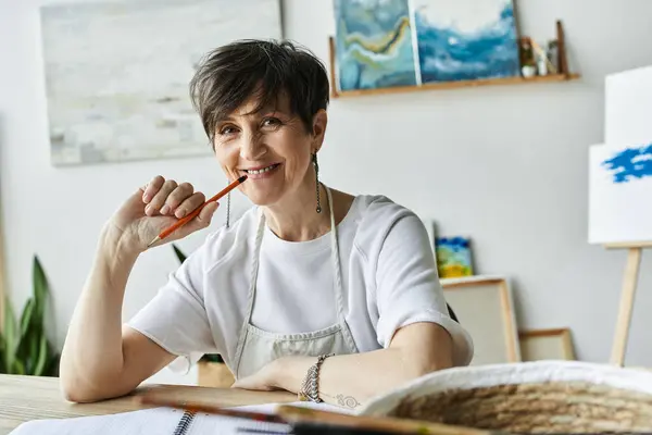 A painter smiles thoughtfully while taking a break in her vibrant art studio. — Stock Photo