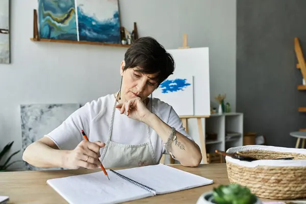 A dedicated artist sketches thoughtfully at her studio table. — Stock Photo