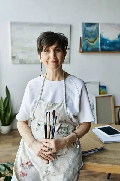 Eine reife Frau genießt die kreative Zeit in ihrem einladenden Kunstatelier, umgeben von ihrer Arbeit. — Stockfoto