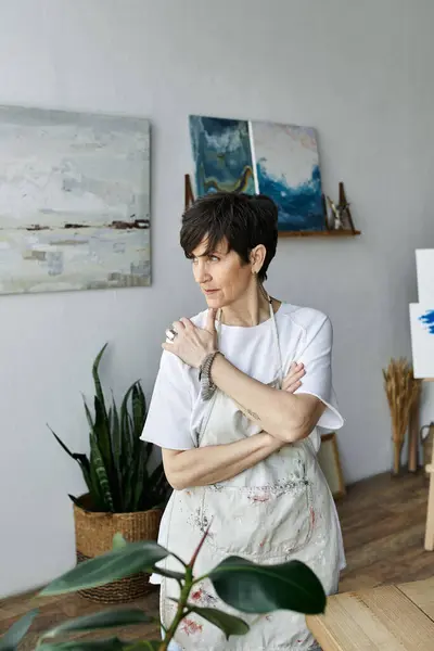 A woman contemplates her artwork in a bright, inspiring studio. — Stock Photo