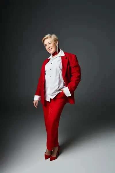 An adult woman showcases sophisticated fashion in a striking red ensemble, perfectly poised. — Stock Photo