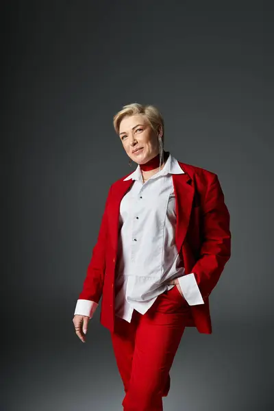 An elegant adult woman stands confidently in a striking red ensemble, showcasing her unique style. — Stock Photo