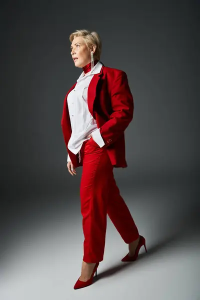 An adult woman strides confidently in a chic red outfit, radiating elegance and style. — Stock Photo